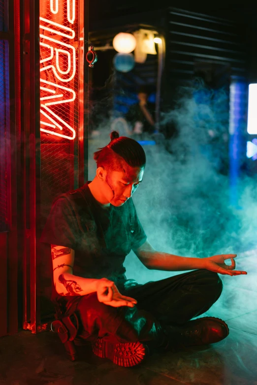 a man sitting on the ground in front of a neon sign, inspired by Liam Wong, trending on pexels, holography, praying with tobacco, photograph of a techwear woman, meditating pose, nightclub