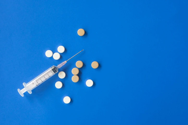 a syll filled with pills on a blue background, inspired by Damien Hirst, trending on pexels, syringe, blue and white and gold, shoulder, a wooden