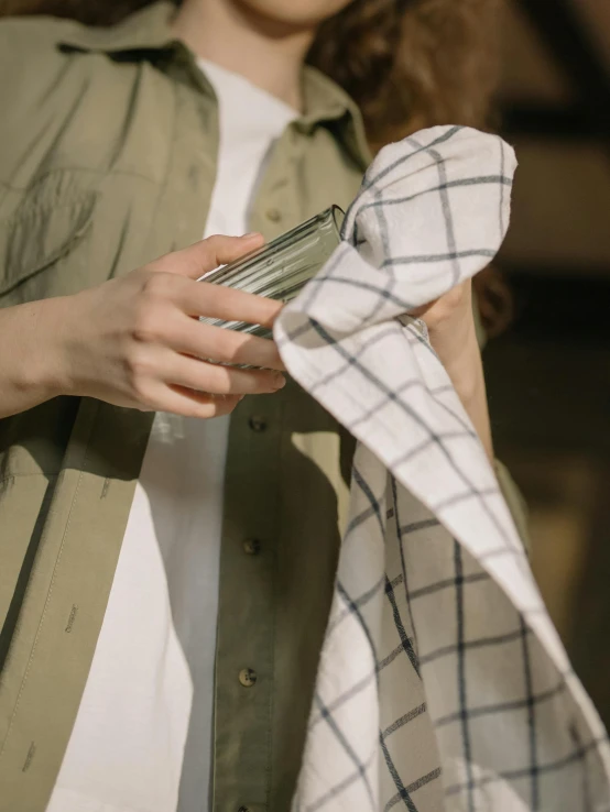 a close up of a person holding a piece of cloth, holding a bottle, wearing clothes, transparent, flannel