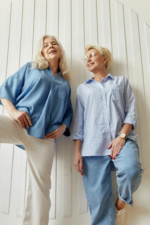 a couple of women standing next to each other, shutterstock, wearing a light blue shirt, pants, age lines, thumbnail