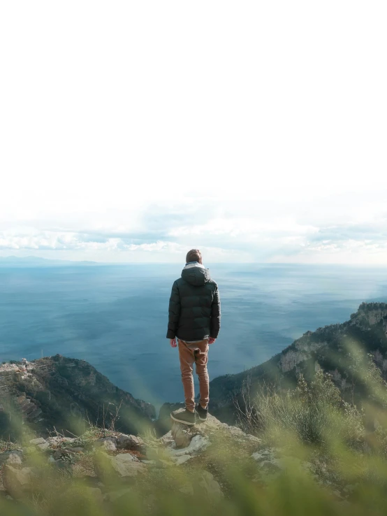 a man standing on top of a mountain looking at the ocean, profile image