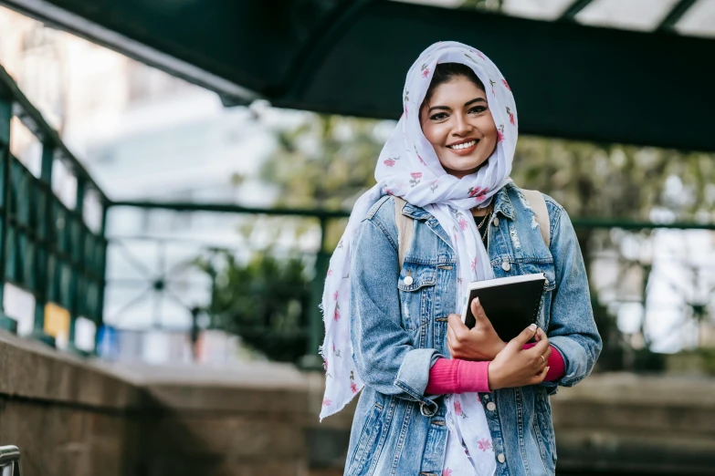 a woman in a hijab is holding a tablet, trending on unsplash, hurufiyya, wearing double denim, post graduate, wearing pink floral chiton, 15081959 21121991 01012000 4k