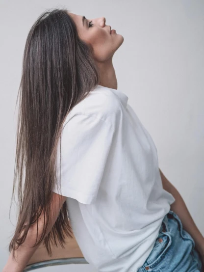 a woman with long hair sitting on a chair, trending on unsplash, plain white tshirt, posed in profile, wearing a baggy, neck zoomed in