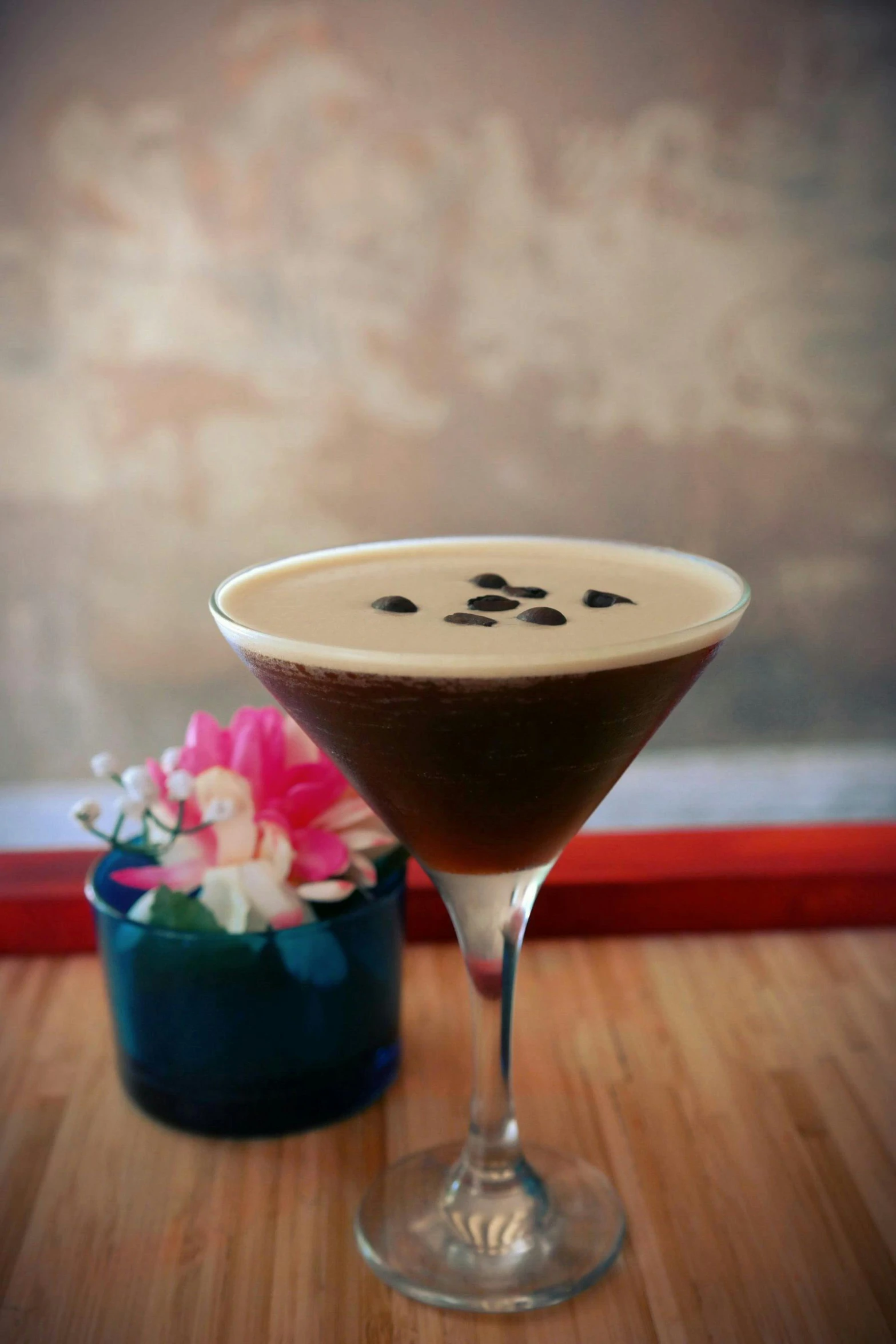 a martini sitting on top of a wooden table, amongst coffee beans and flowers, iced latte, black lotus, chocolate