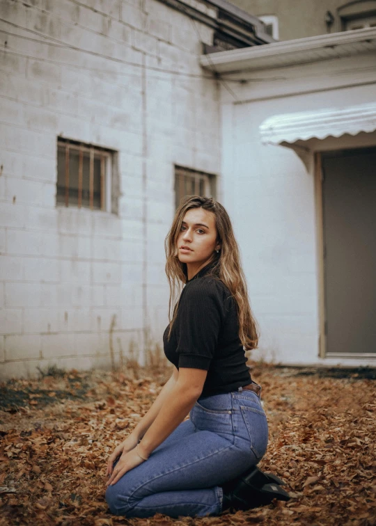 a woman sitting on the ground in front of a building, wearing a dark shirt and jeans, profile image, portrait featured on unsplash, portrait sophie mudd