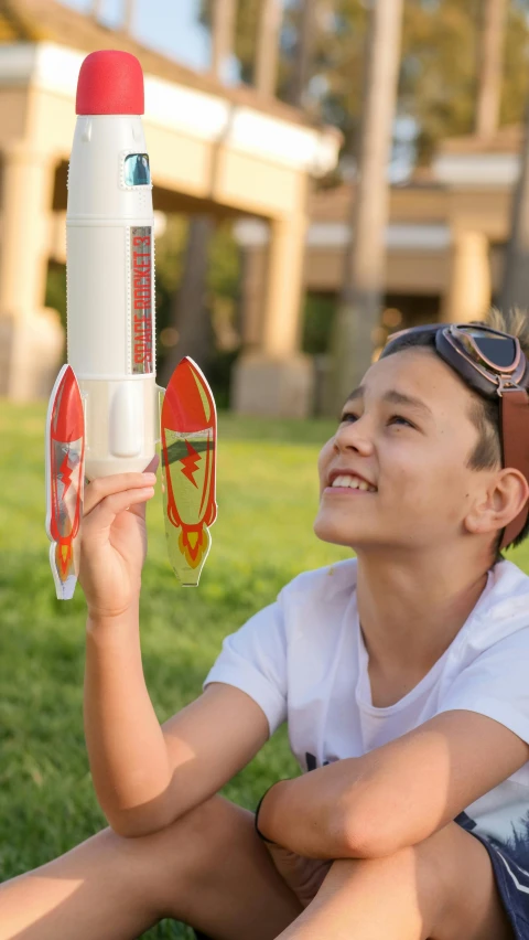 a couple of kids sitting on top of a lush green field, unsplash, conceptual art, spacex starship rocket launch, next to it is a toy ray gun, avatar image, mid closeup