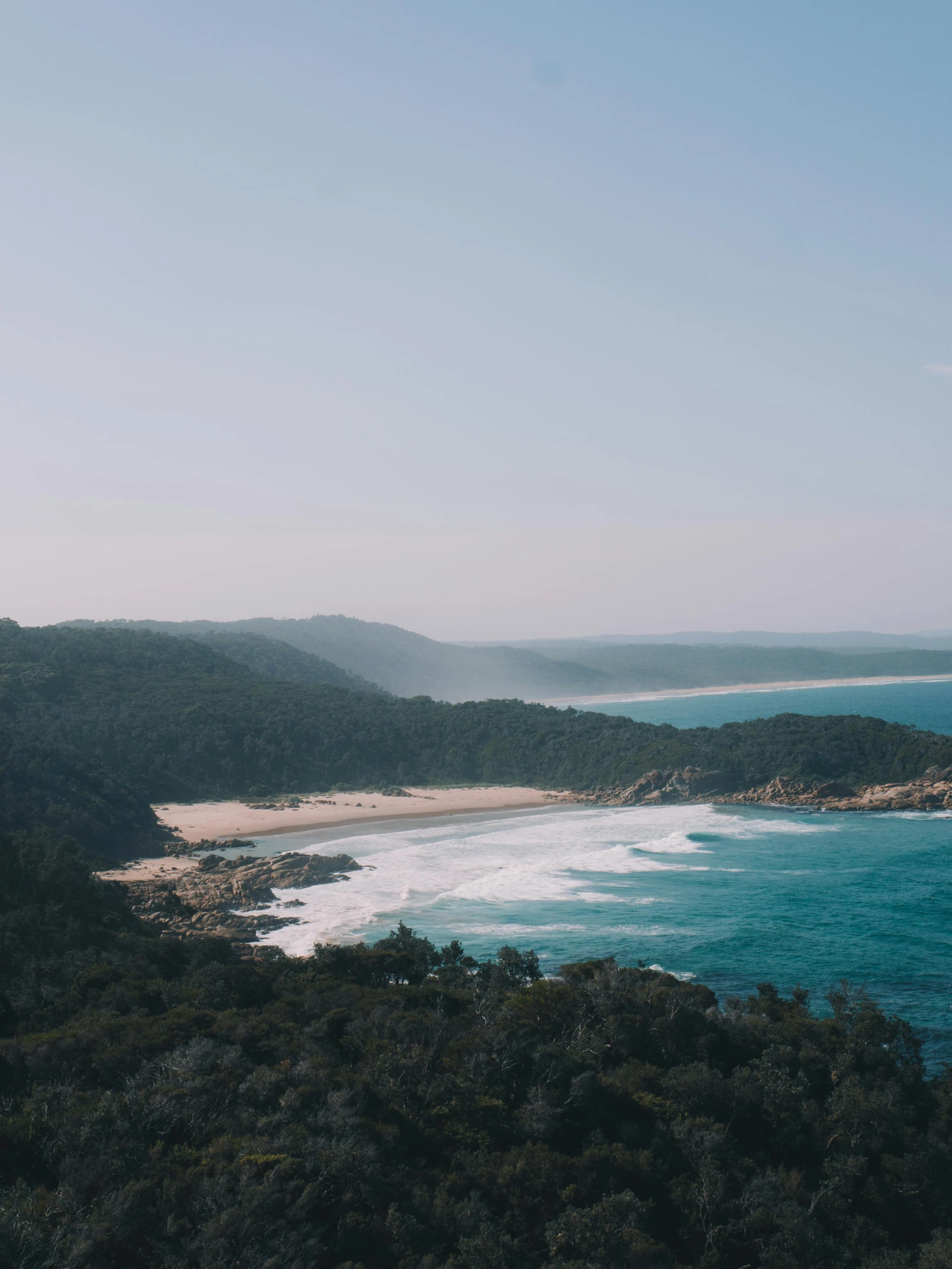 a large body of water sitting on top of a lush green hillside, unsplash contest winner, australian beach, pine forests, dreamy hazy, beaching