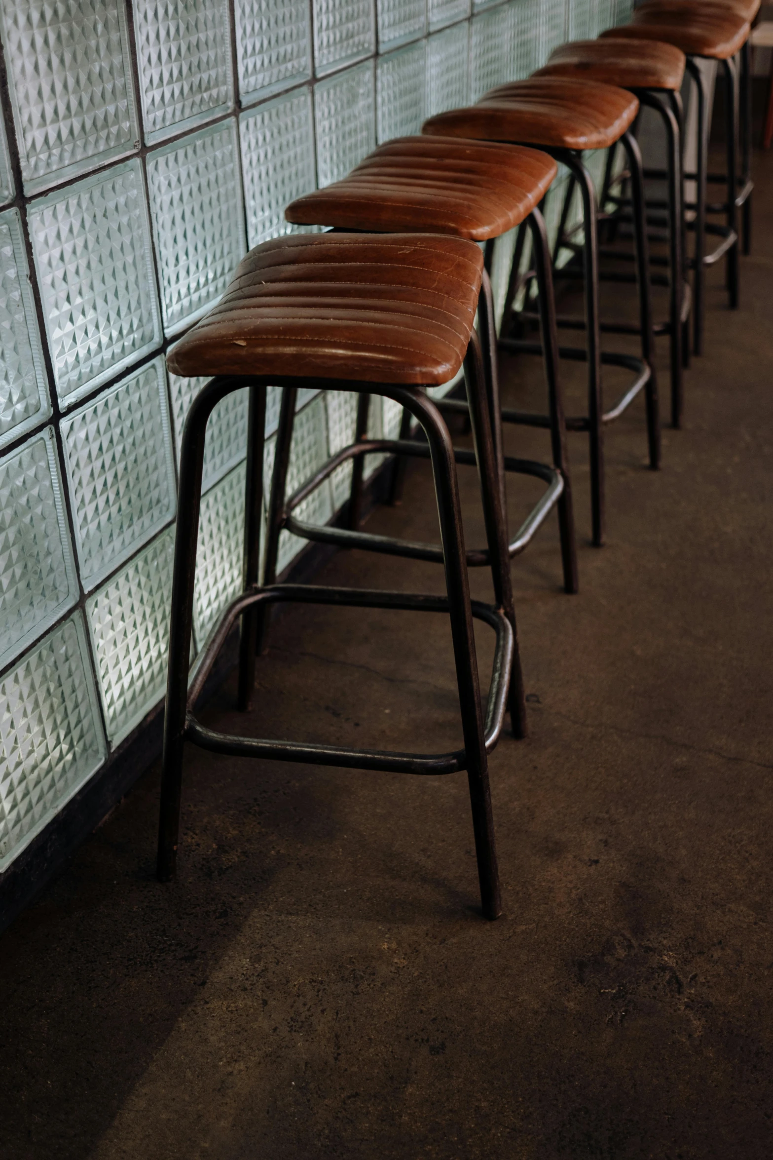 a row of bar stools lined up against a wall, a portrait, unsplash, wearing leather, square, faded worn, portrait n - 9