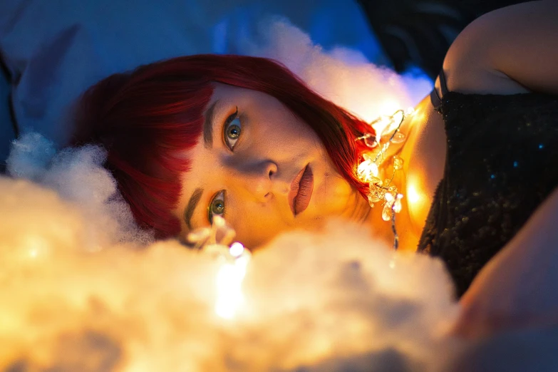 a woman laying on top of a bed covered in snow, an album cover, by Julia Pishtar, unsplash, red wig, lights and smoke, cosplay photo, on clouds