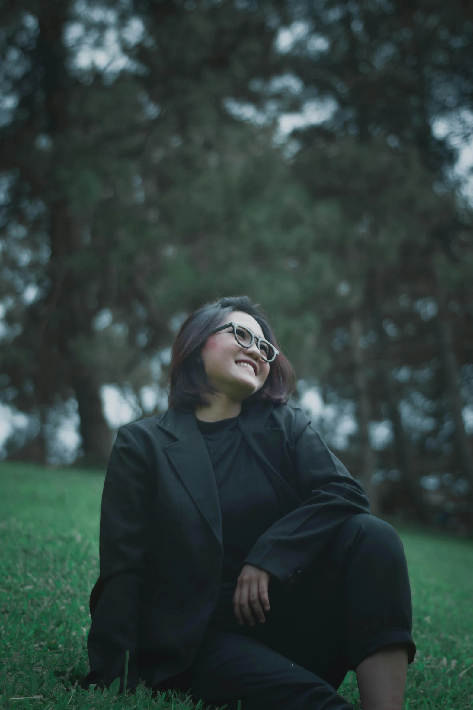 a woman sitting on top of a lush green field, an album cover, pexels contest winner, realism, in suit with black glasses, mutahar laughing, in a black hoodie, asian women