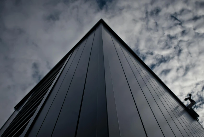 a tall building with a sky background, inspired by Tadao Ando, unsplash, minimalism, black steel buildings, triangle, stealth