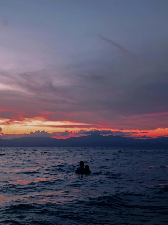 a person swimming in the ocean at sunset, by Robbie Trevino, unsplash contest winner, sumatraism, 4 k cinematic still, slight overcast, volcanoes in the background, pink skies