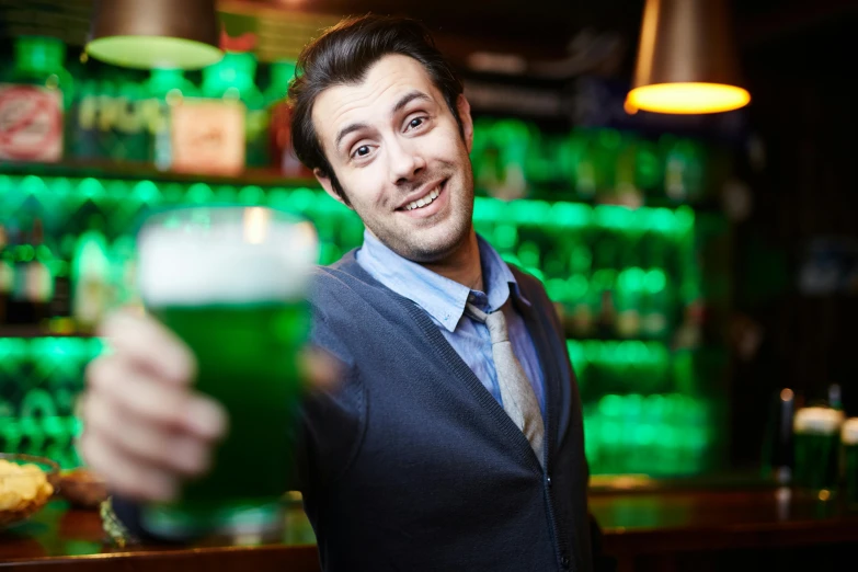 a man holding a glass of beer in front of a bar, a photo, shutterstock, happening, wearing green clothing, giddy smirk, irish, instagram picture