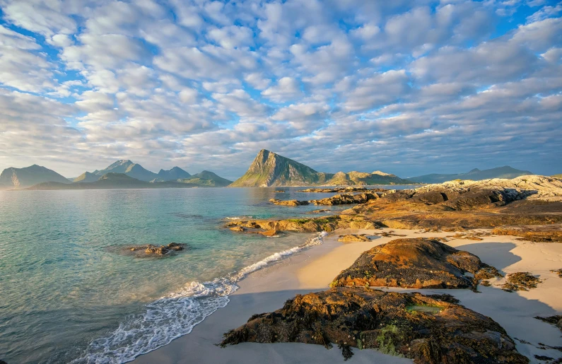 a large body of water next to a sandy beach, by Roar Kjernstad, pexels contest winner, hurufiyya, mountains and ocean, summer morning light, many islands, conde nast traveler photo