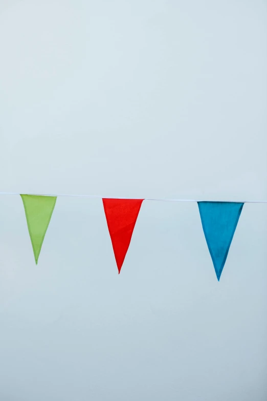 a row of colorful flags hanging from a line, 3 - piece, triangle, green and red, unlit