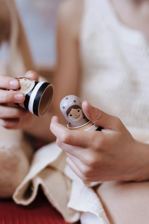 a close up of a person holding a cell phone, inspired by Nara Yoshitomo, trending on pexels, folk art, wood cups, wearing two metallic rings, tiny girl looking on, hibernation capsule close-up