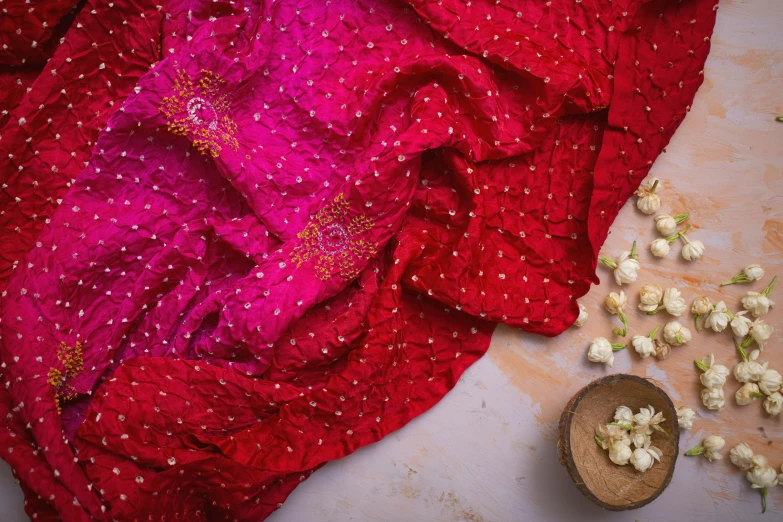 a red sari sitting on top of a table next to a bowl of flowers, pexels, process art, petal pink gradient scheme, polka dot, crimson clothes, beaded embroidery