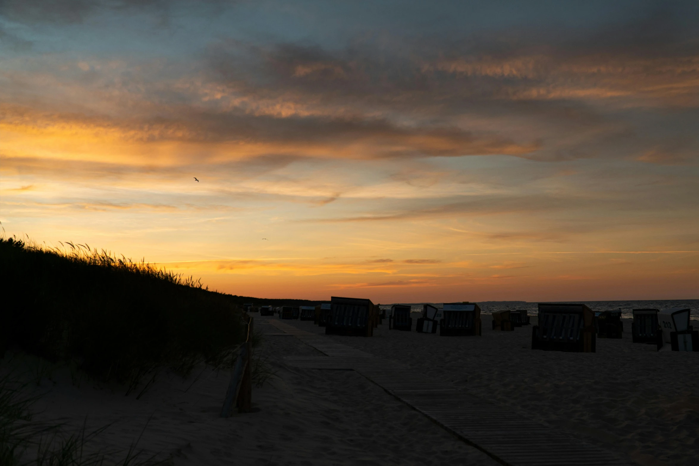 a group of beach chairs sitting on top of a sandy beach, by Jan Tengnagel, pexels contest winner, happening, sunset panorama, profile image, night photo, lower saxony