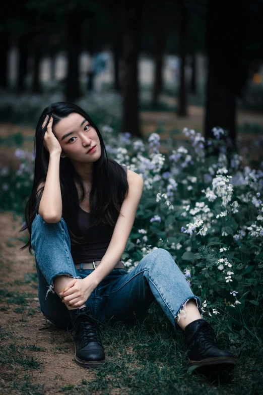 a woman sitting on the ground in a field of flowers, by Wen Zhenheng, pexels contest winner, realism, 🤤 girl portrait, wearing jeans, frown fashion model, in a city park