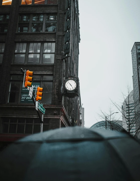 a clock that is on the side of a building, a photo, trending on pexels, traffic light on, industrial gotham city, gray sky, viral image