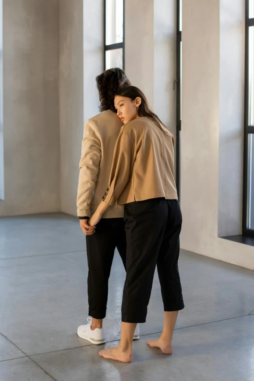 a couple of women standing next to each other, by Nina Hamnett, wear's beige shirt, bent - over posture, cropped shirt with jacket, private moment