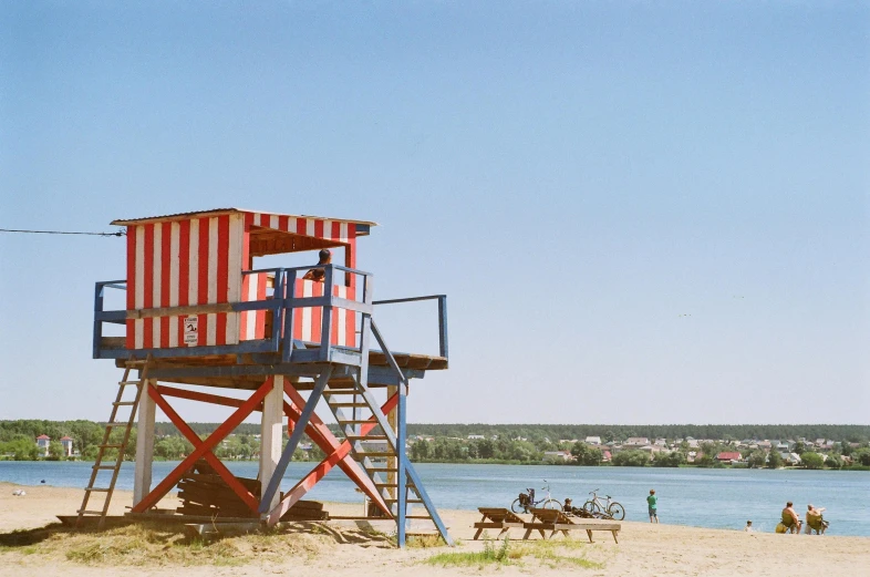 a lifeguard tower sitting on top of a sandy beach, by Attila Meszlenyi, lagoon, medium format, everyone having fun, red and blue