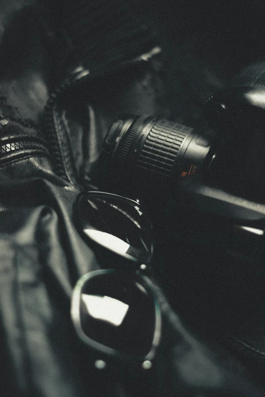 a camera sitting on top of a black bag, by Adam Marczyński, unsplash, visual art, wearing shiny black goggles, detective clothes, close up shot from the top, banner