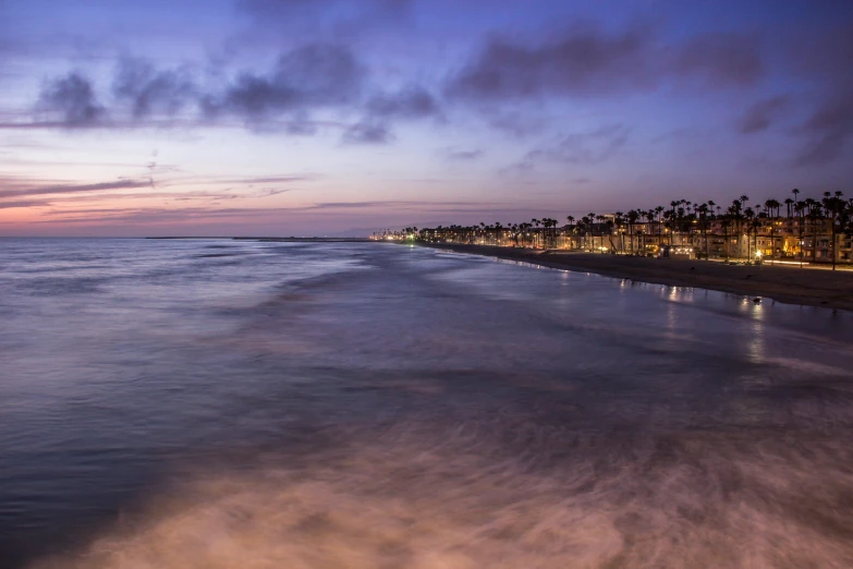 a large body of water next to a beach, by Ryan Pancoast, unsplash contest winner, renaissance, blue hour, oceanside, city in the distance, peter hurley