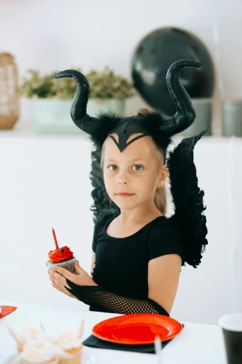 a little girl sitting at a table with a cupcake, pexels contest winner, long tail with horns, female disney villain, profile image, costumes