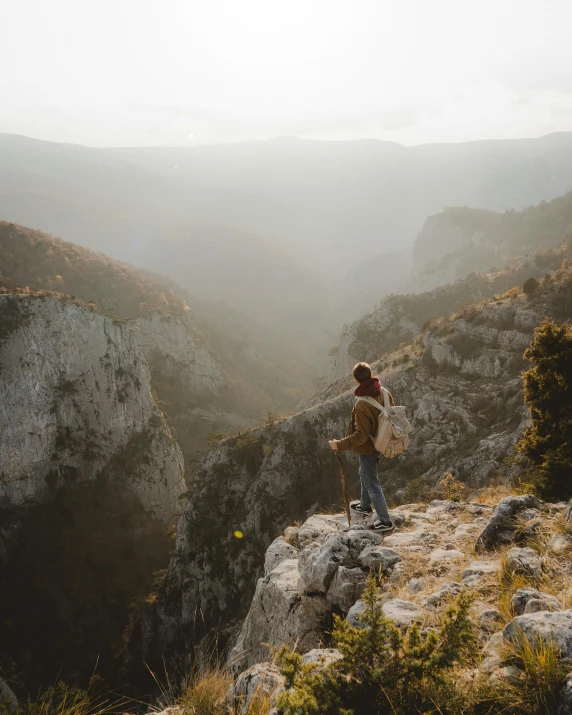 a person standing on top of a mountain, by Emma Andijewska, pexels contest winner, happening, canyon, hiking cane, a handsome, southern european scenery