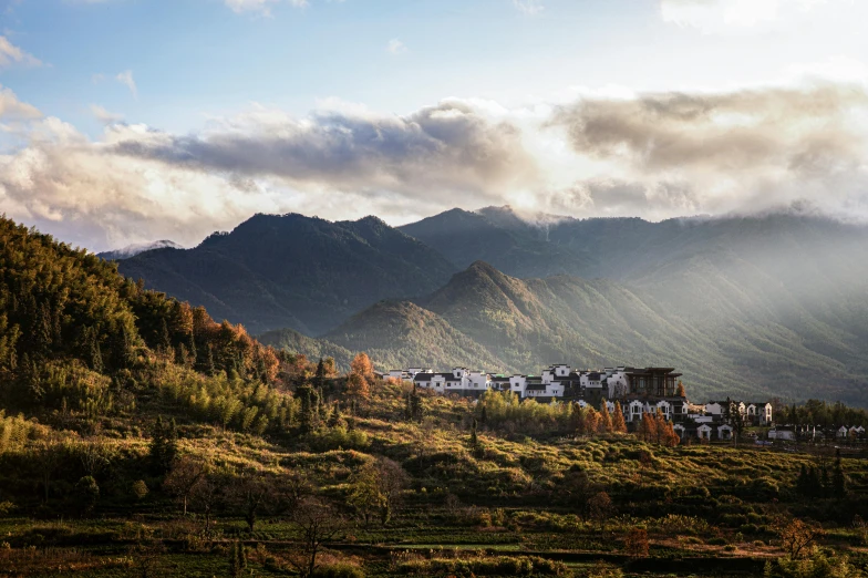 a herd of sheep grazing on top of a lush green hillside, by Jessie Algie, unsplash contest winner, mingei, tibetan inspired architecture, autumn mountains, dreamy chinese town, late afternoon sun