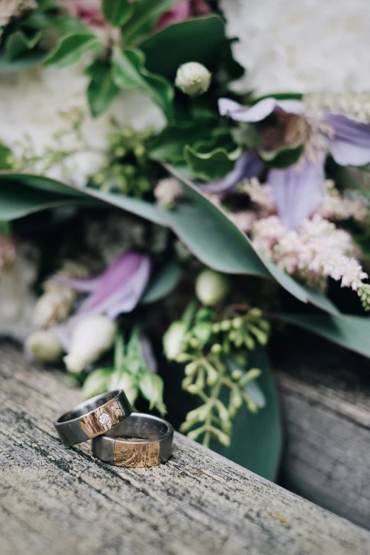 a couple of wedding rings sitting on top of a wooden bench, by Elsie Few, renaissance, herbs and flowers, carefully crafted, rugged details, “ iron bark