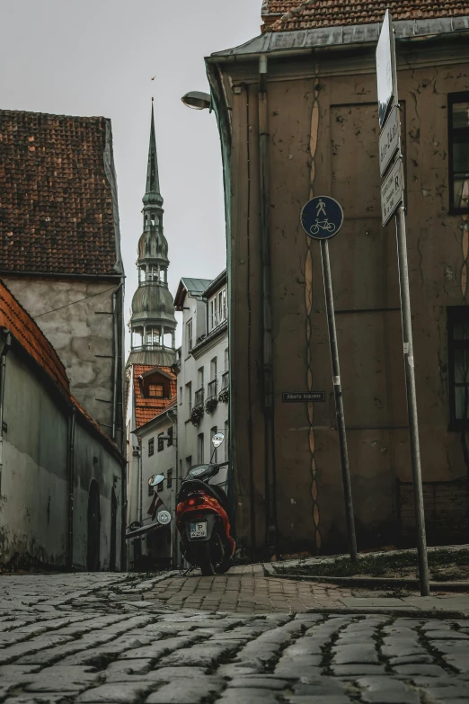 a motorcycle is parked on a cobblestone street, pexels contest winner, graffiti, tall spires, tallinn, dingy city street, distant photo