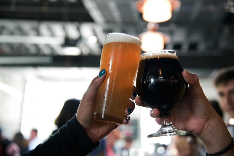 a close up of a person holding a glass of beer, black and reddis, woman holding another woman, hands in the air, black and brown