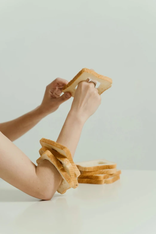 a woman sitting at a table with a sandwich in her hand, inspired by Sarah Lucas, trending on pexels, conceptual art, curved blades on each hand, squares, formless brests, yeast