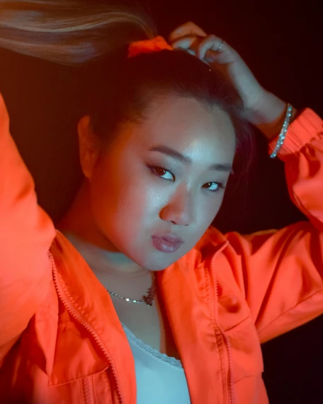 a woman in an orange jacket posing for a picture, an album cover, inspired by Yang J, unsplash, realism, bisexual lighting, bbwchan, half asian, ☁🌪🌙👩🏾