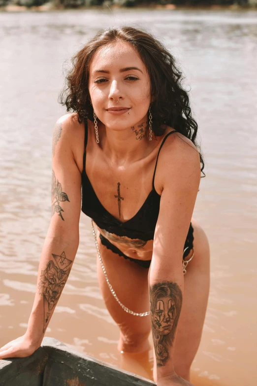 a woman in a bikini standing in a body of water, a tattoo, trending on pexels, renaissance, 2 4 year old female model, on the sand, headshot photo, piercing