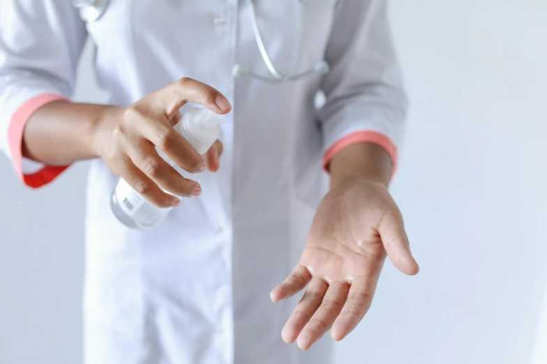 a close up of a person holding a bottle of hand sanitizer, pexels, wearing lab coat and a blouse, misting, open palm, brown