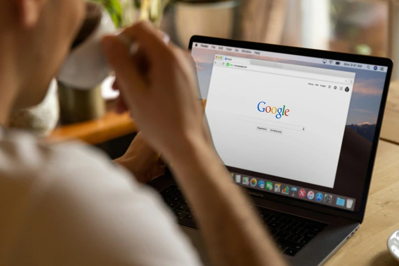 a person sitting at a table with a laptop and a cup of coffee, pexels, renaissance, google logo, looking at monitor, zoomed in, chrome