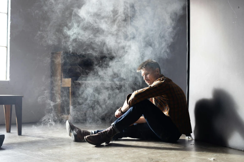 a man sitting on the floor smoking a cigarette, trending on pexels, visual art, light over boy, cold studio lighting, contemplating, :6 smoke grenades