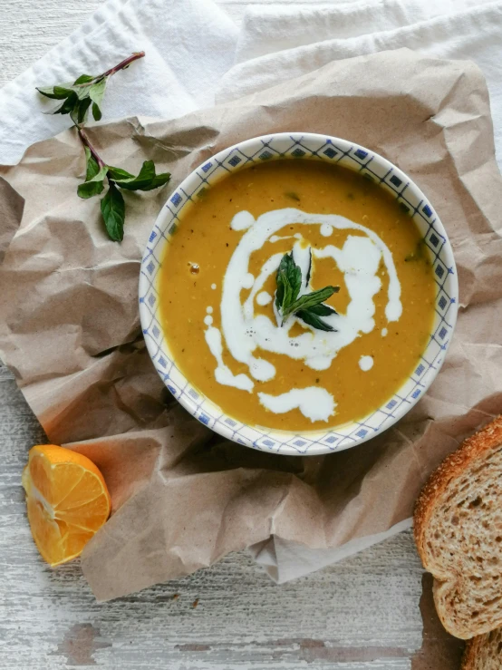 a bowl of soup next to a slice of bread, unsplash contest winner, with lemon skin texture, pumpkin, mint, high quality product image”