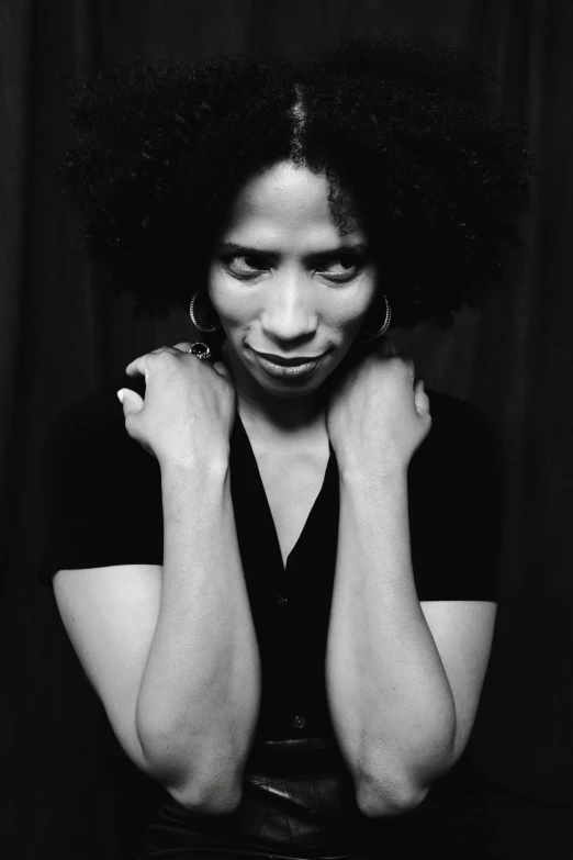 a black and white photo of a woman with curly hair, inspired by Carrie Mae Weems, with index finger, looking defiantly at the camera, square, taken in the late 2000s