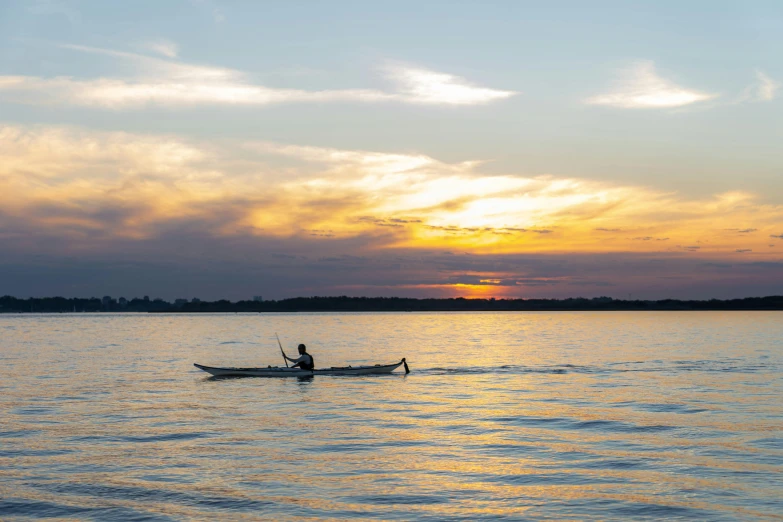 a person in a boat on a body of water, a picture, in the evening