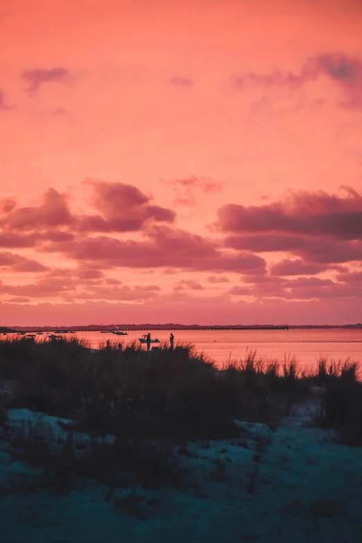 a couple of people standing on top of a sandy beach, pink skies, shades of aerochrome, the emerald coast, salt dunes