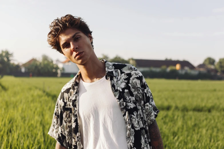 a man standing in a field of tall grass, an album cover, inspired by John Luke, trending on pexels, hyperrealism, floral clothes, confident smirk, leonardo fioravanti, dressed in a white t-shirt