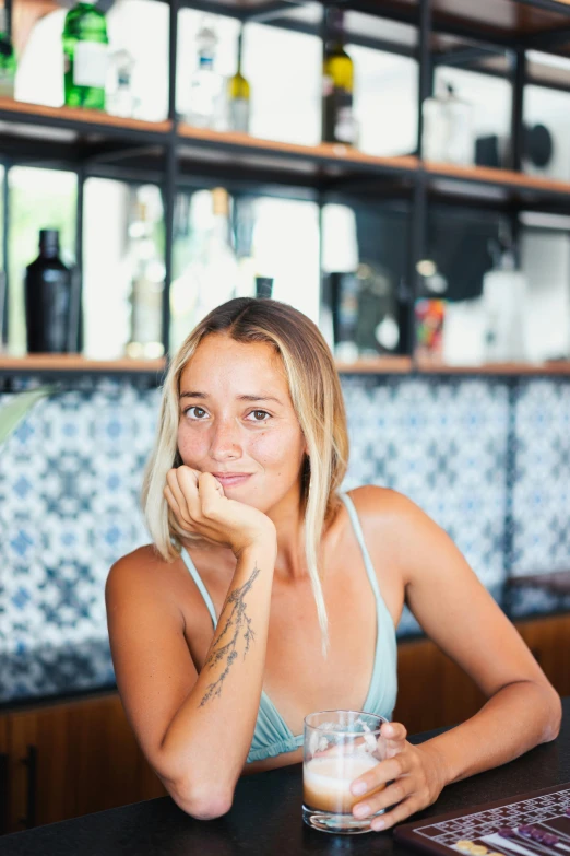 a woman sitting at a bar with a drink, a portrait, by Jessie Alexandra Dick, pexels contest winner, slightly tanned, bali, halfbody headshot, square