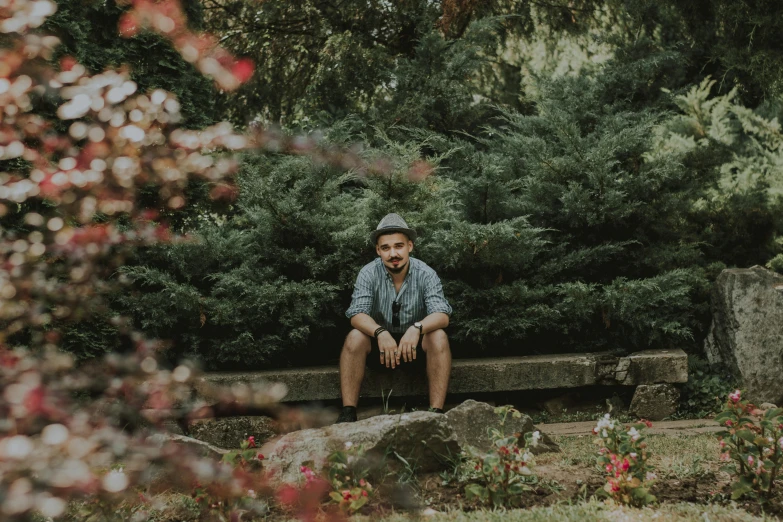 a man sitting on a stone bench in a park, by Andrew Stevovich, pexels contest winner, portrait pose, covered in plants, avatar image, casual pose