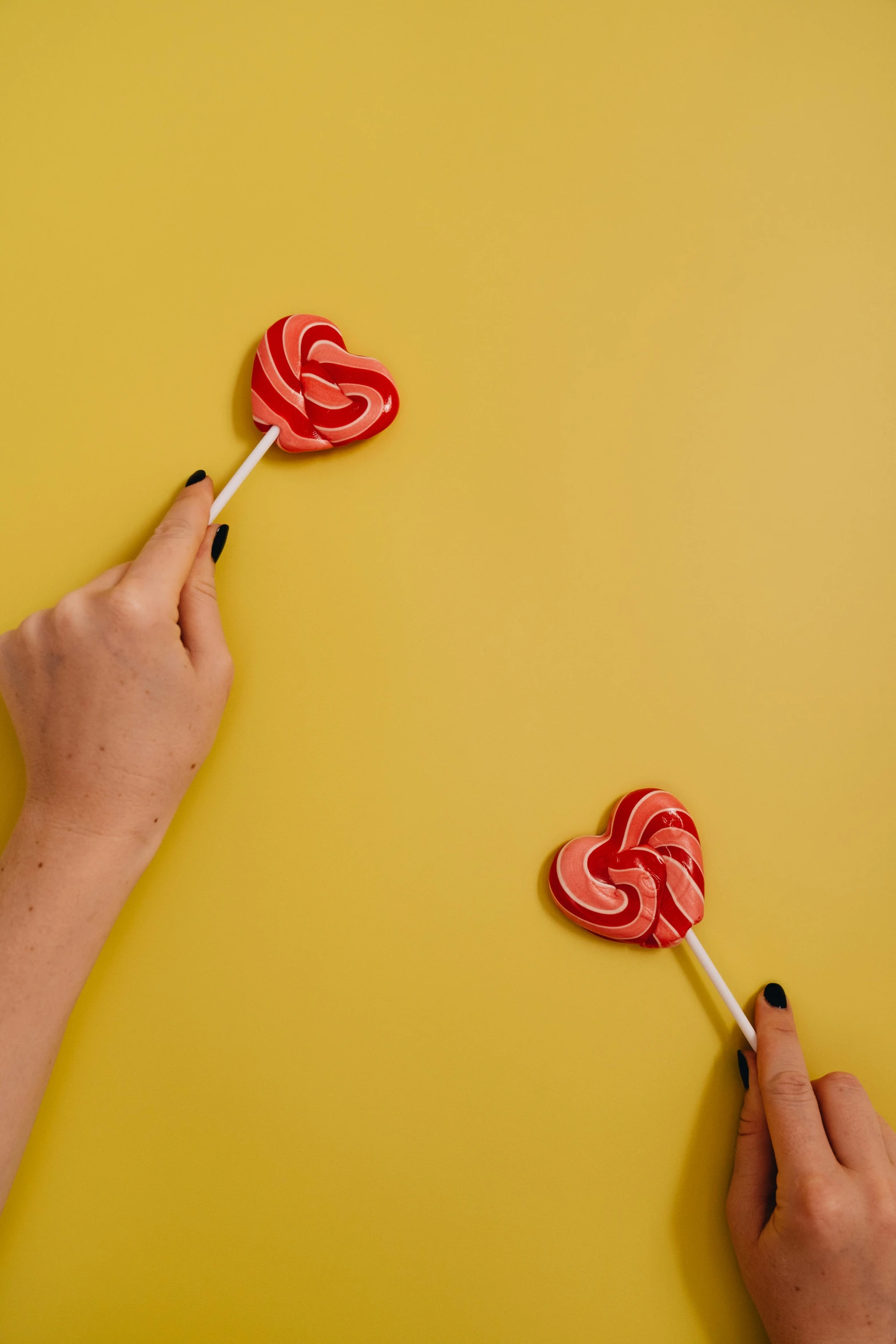 two hands holding lollipops on a yellow background, pexels, instagram picture, pale red, romantic lead, made of food