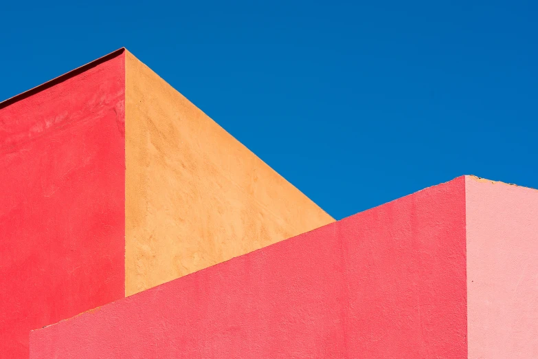 a red and yellow building with a blue sky in the background, a minimalist painting, unsplash contest winner, pink concrete, three colors, ignant, geometrical