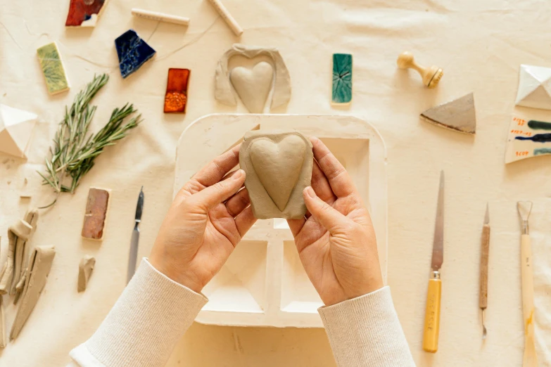 a woman making a heart out of clay, a marble sculpture, inspired by Sarah Lucas, trending on pexels, rectangle, fossil ornaments, product introduction photo, thumbnail